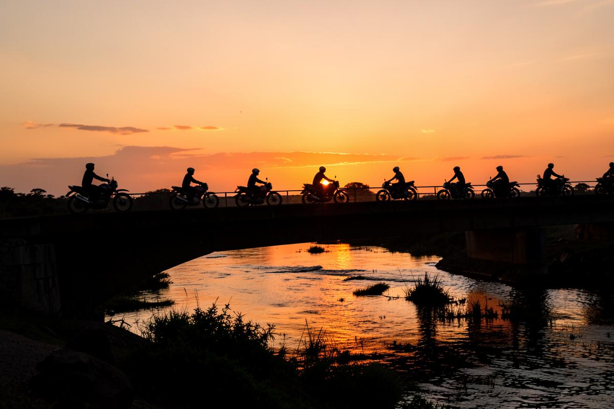 Riders crossing a bridge over the Zambezi at sunset